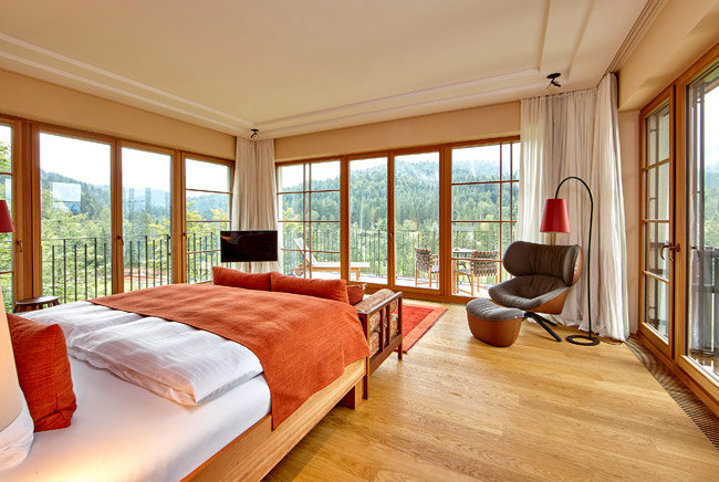 Pokój hotelowy w Schloss Elmau z łóżkiem i fotelem z widokiem na las